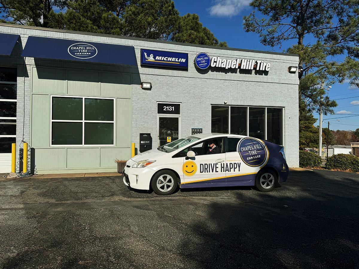 Car parked in front of a tire shop with signs. The car has a