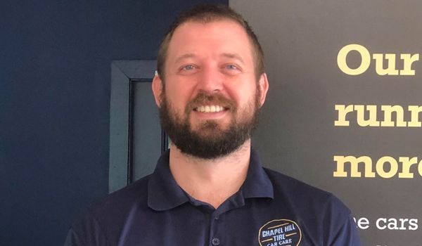 Man with a beard in a blue polo shirt smiles in front of text on a dark background.