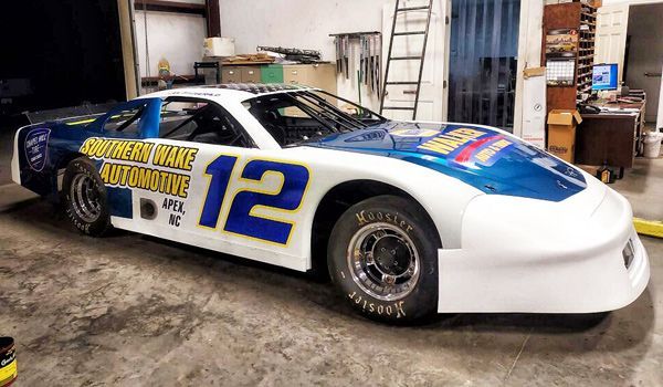 Race car with blue and white paint, number 12, inside a garage.