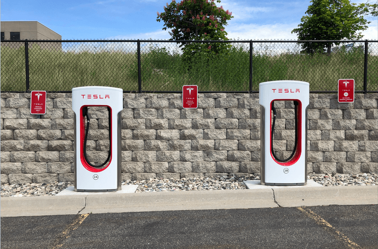 Two tesla charging stations in front of a brick wall
