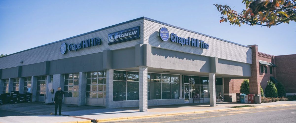 Exterior of a Pearle Vision store. The building is gray with blue signage. A person stands outside.