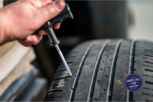 Hand repairing a tire with a tool, close-up shot of the tire with tread marks.