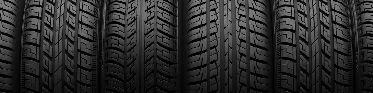 Close-up of a stack of black car tires with detailed tread patterns.