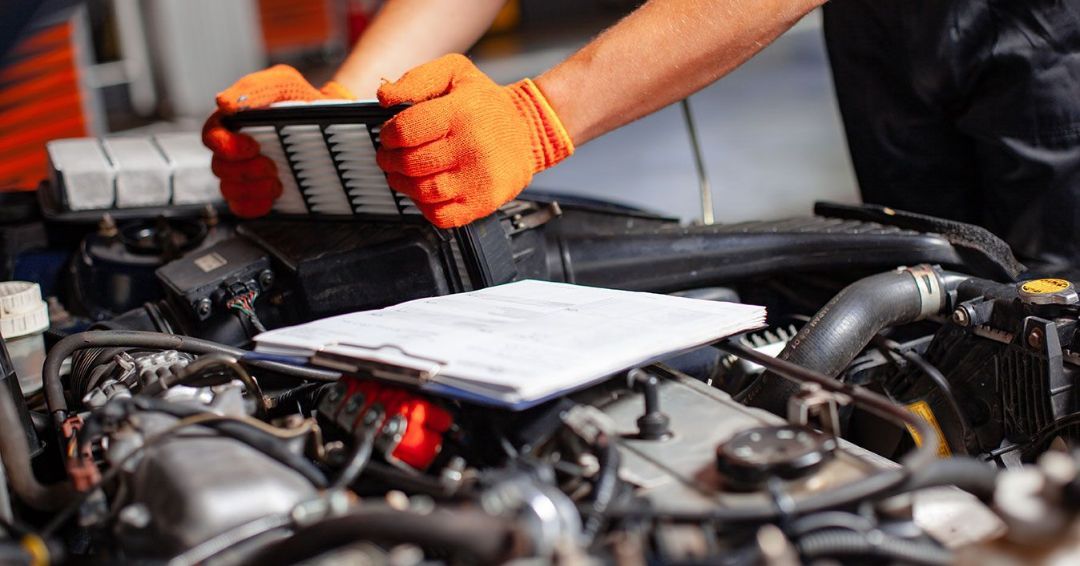 A man wearing orange gloves is working on a car engine.
