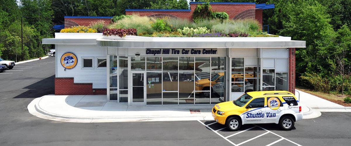 Drive-thru bank building with glass entrance and a yellow service car parked outside.