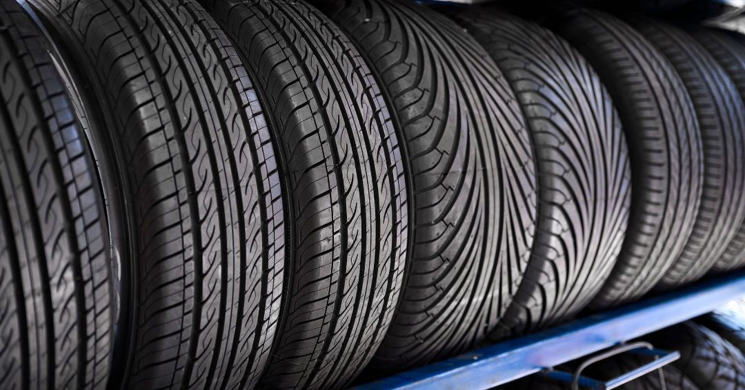 Row of black car tires on a blue shelf, angled towards the viewer.
