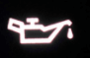 A close up of a oil warning light on a black background.
