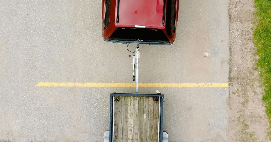 An aerial view of a car pulling a trailer on a road.
