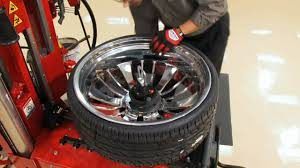 Mechanic using tire machine to change a shiny silver rim and tire.