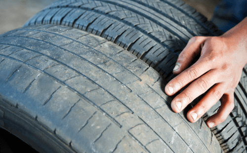 A person is holding a tire with their hands.