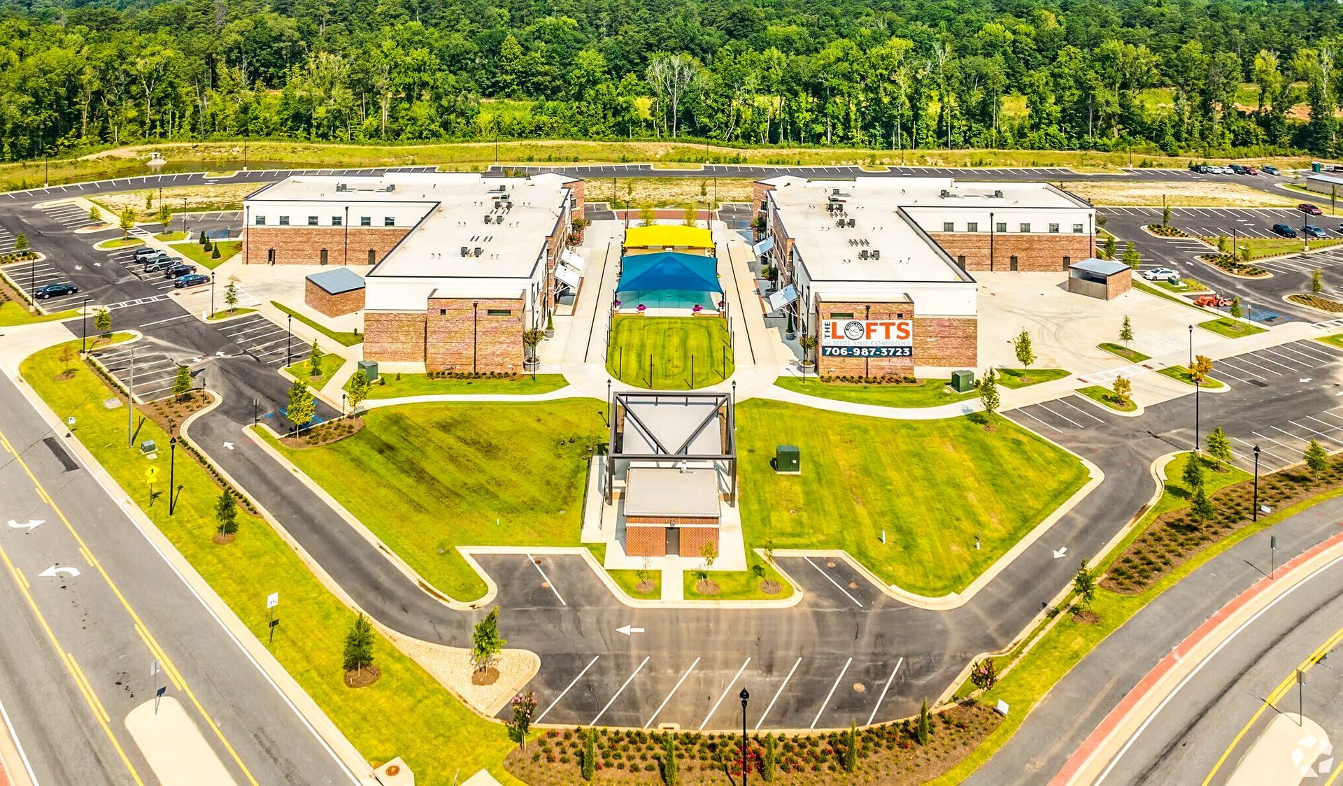 Aerial view of a modern school campus with brick buildings, parking lots, and surrounding trees