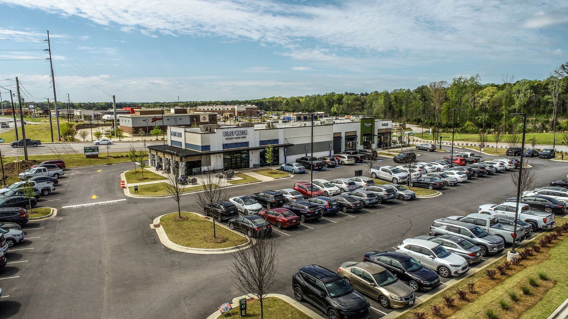 Aerial view of a large car dealership lot with rows of parked cars and a modern showroom building
