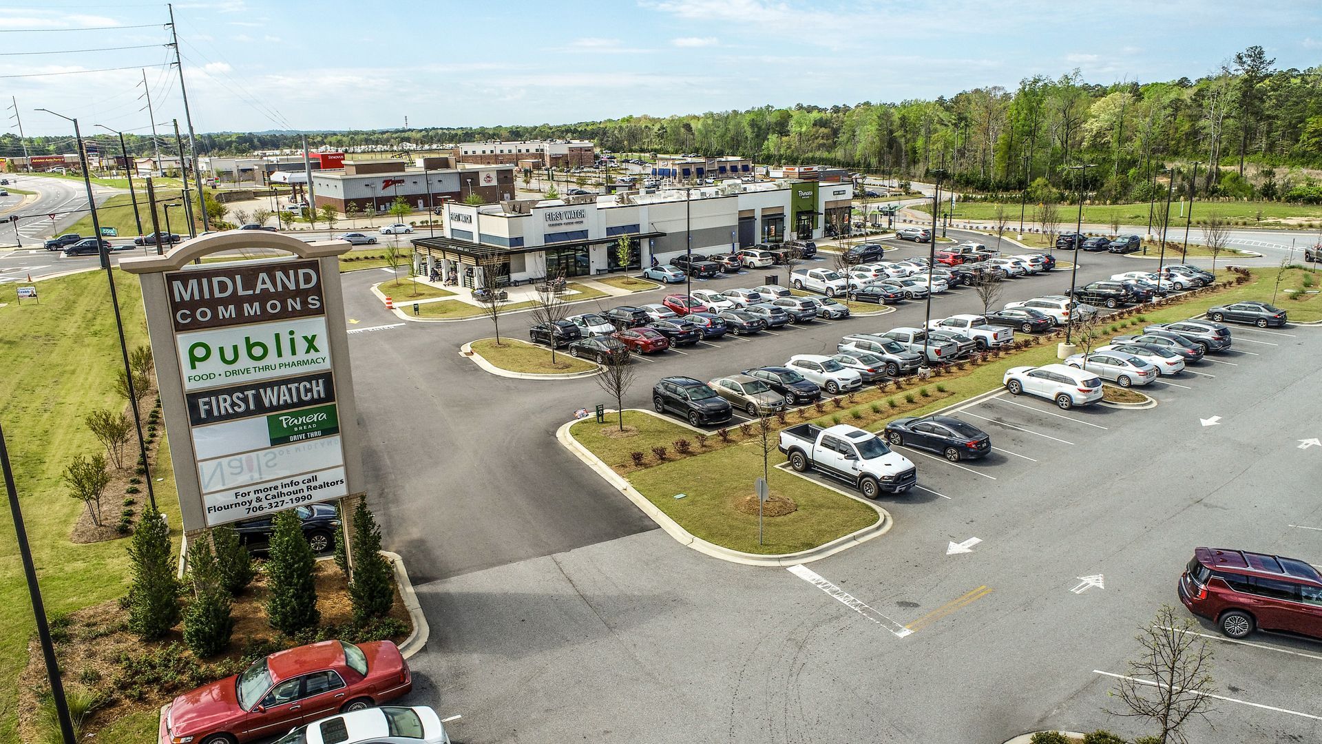 Aerial view of a Publix shopping plaza with parking lot full of cars and nearby roads