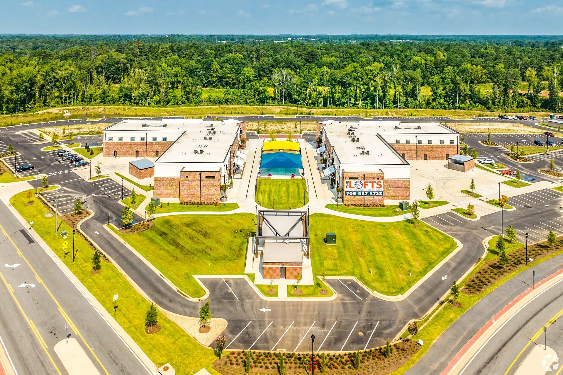 Aerial view of a modern office complex with parking lots, roads, and a central courtyard surrounded by trees