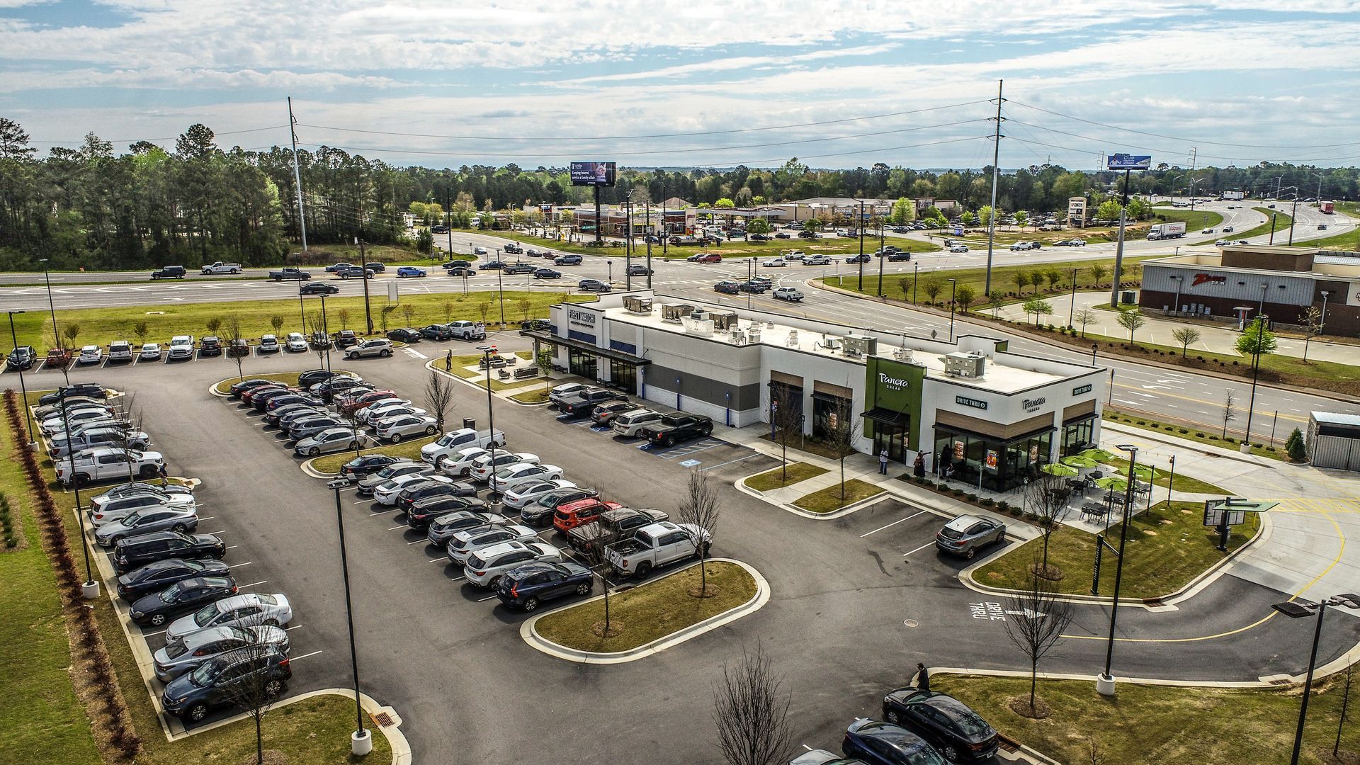 Aerial view of a parking lot and modern commercial buildings on a cloudy day.