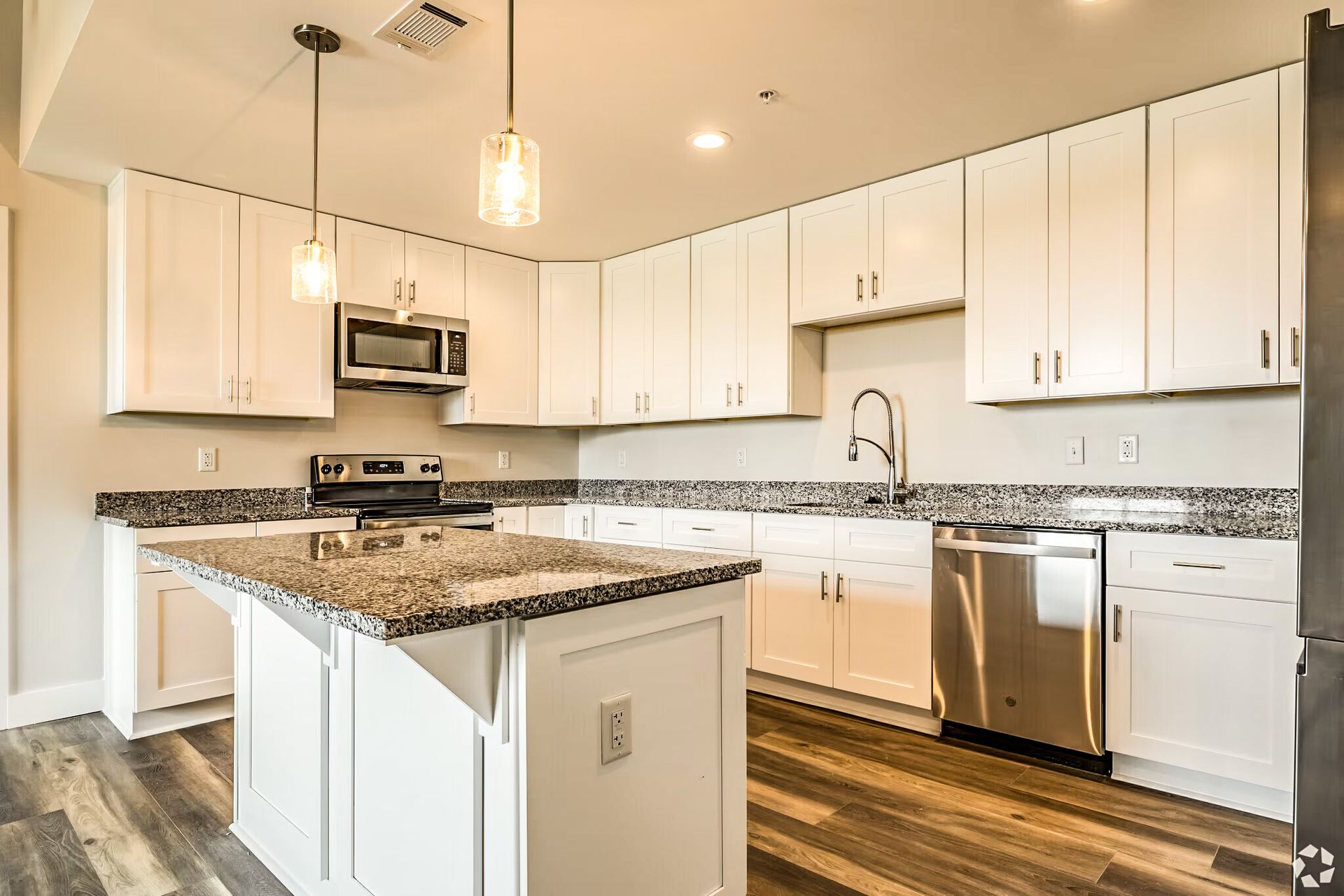 Bright modern kitchen with white cabinets, granite island, stainless appliances, and wood-look floors