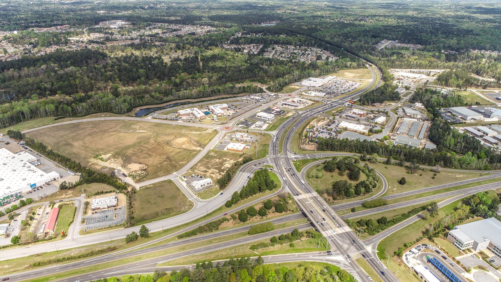 Aerial view of a sprawling construction site with roads, buildings, and surrounding green trees.