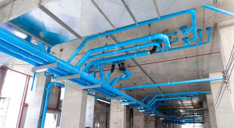 A Bunch Of Blue Pipes Are Hanging From The Ceiling Of A Building — Chad Taylor Plumbing In Forster, NSW