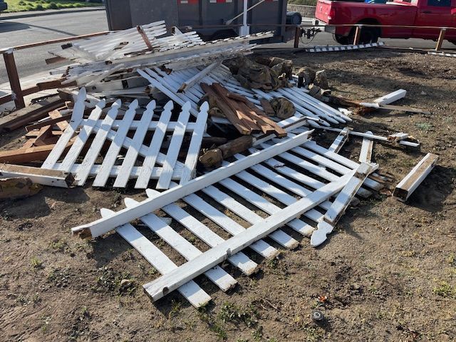 A pile of white picket fence is laying on the ground