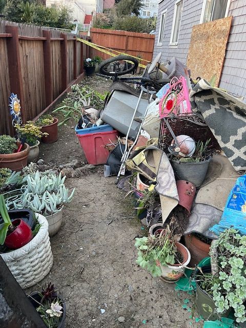 A backyard filled with lots of potted plants and junk.