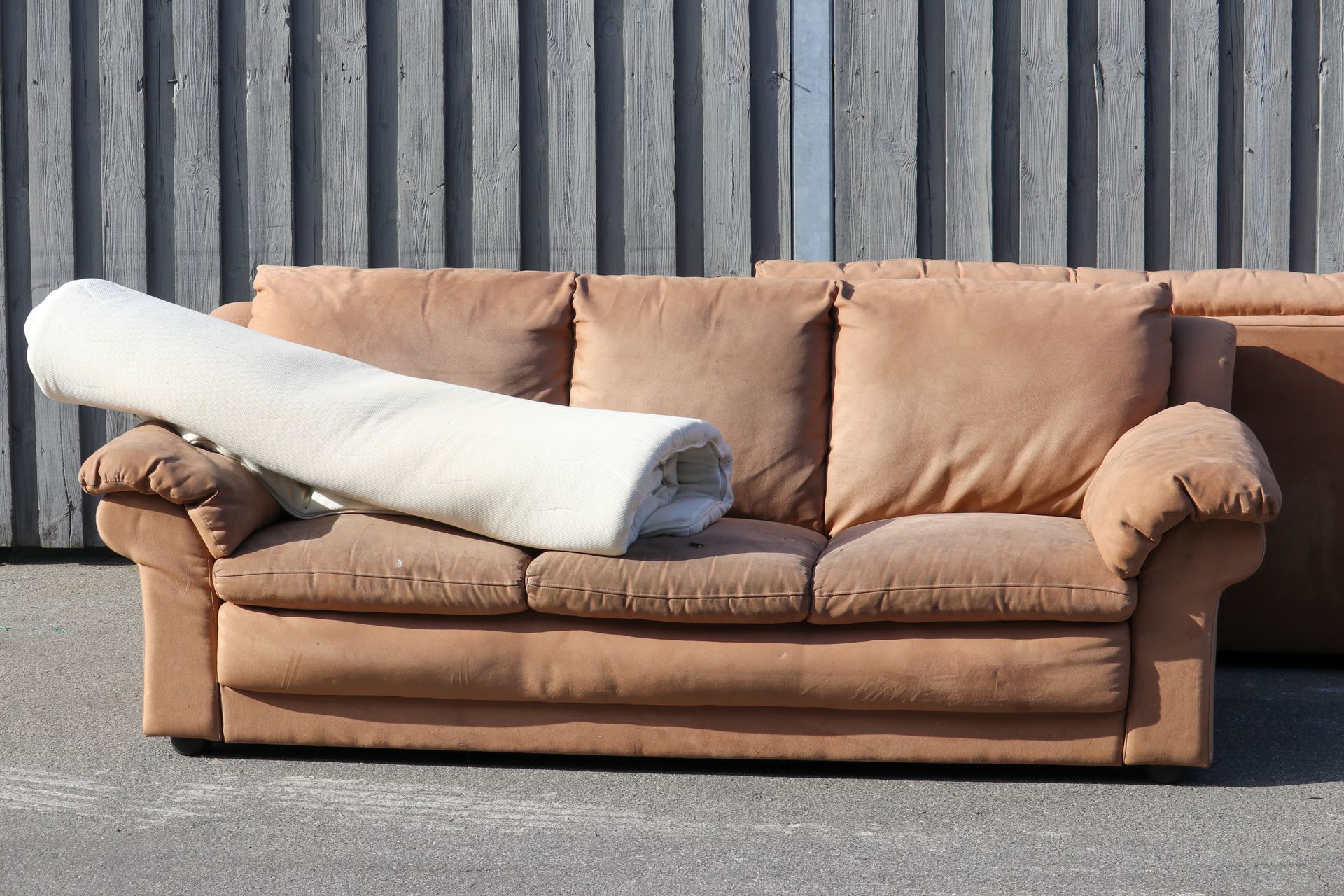 A brown couch with a rug on top of it