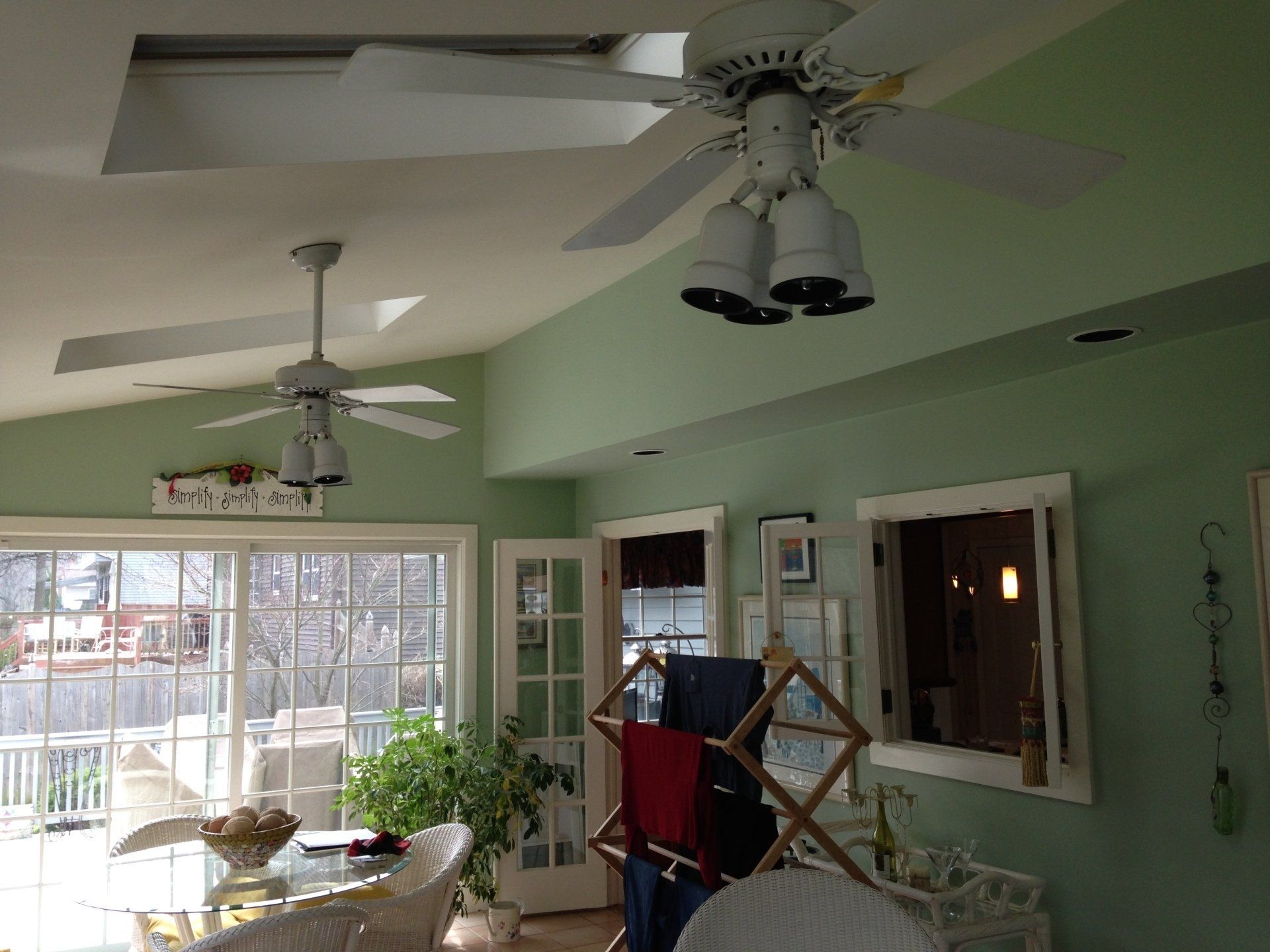A living room with green walls and a ceiling fan