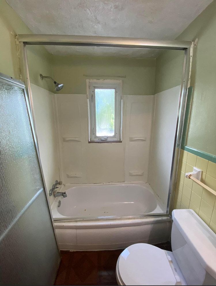 A bathroom with a tub , toilet and shower.