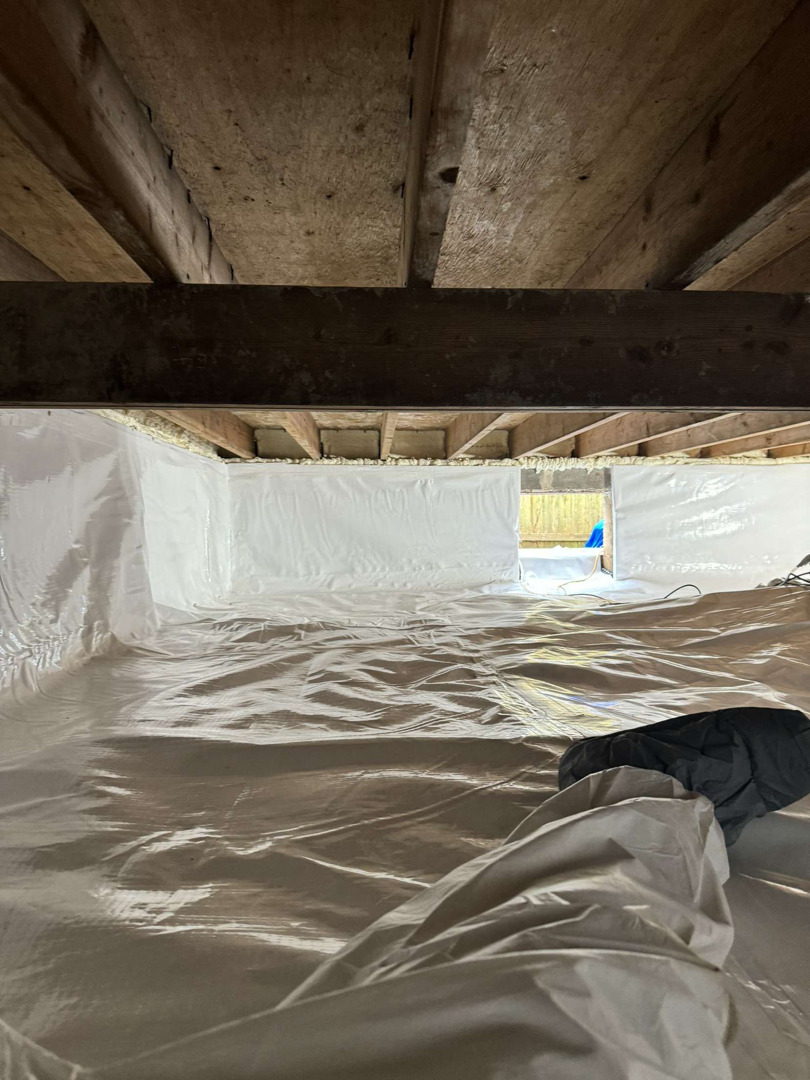 A person is standing in a basement covered in plastic.