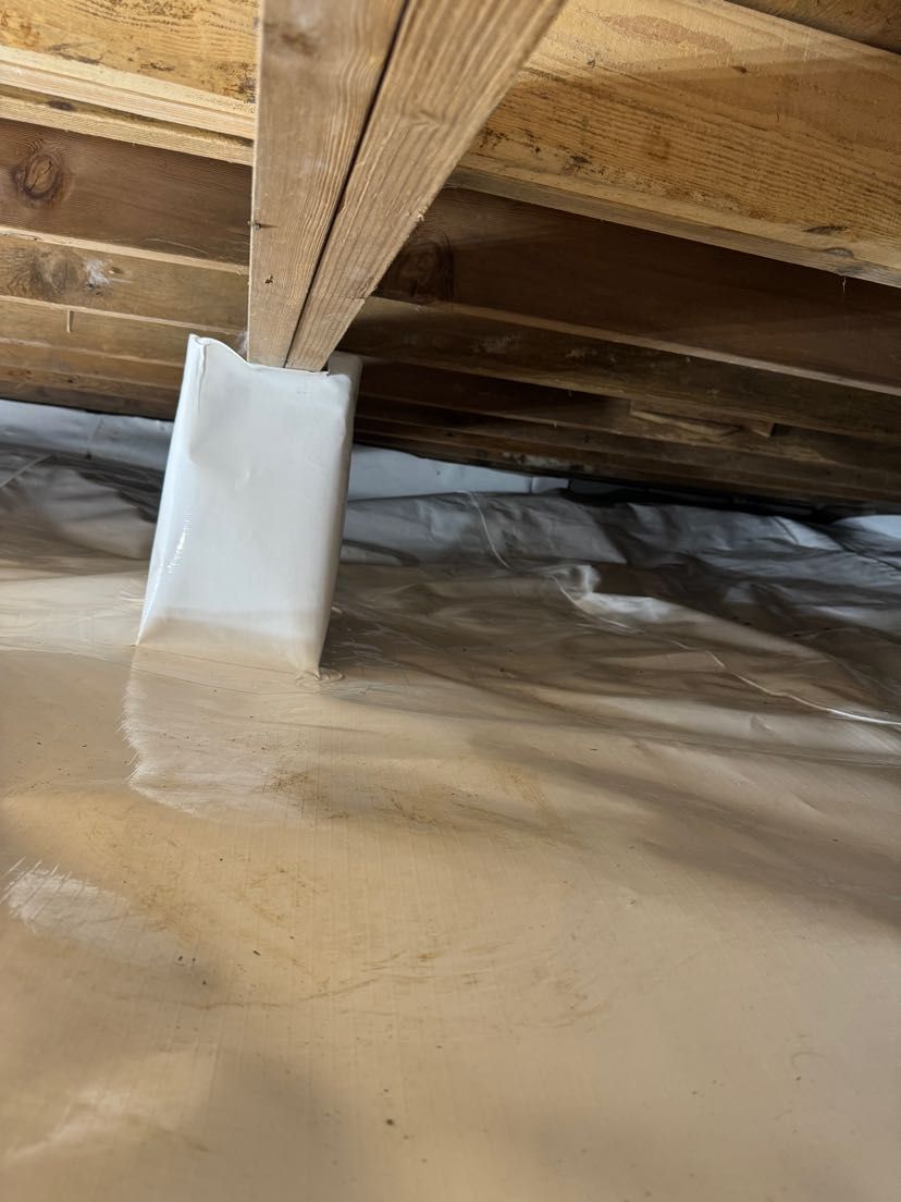 A close up of a basement with plastic covering and wooden beams.