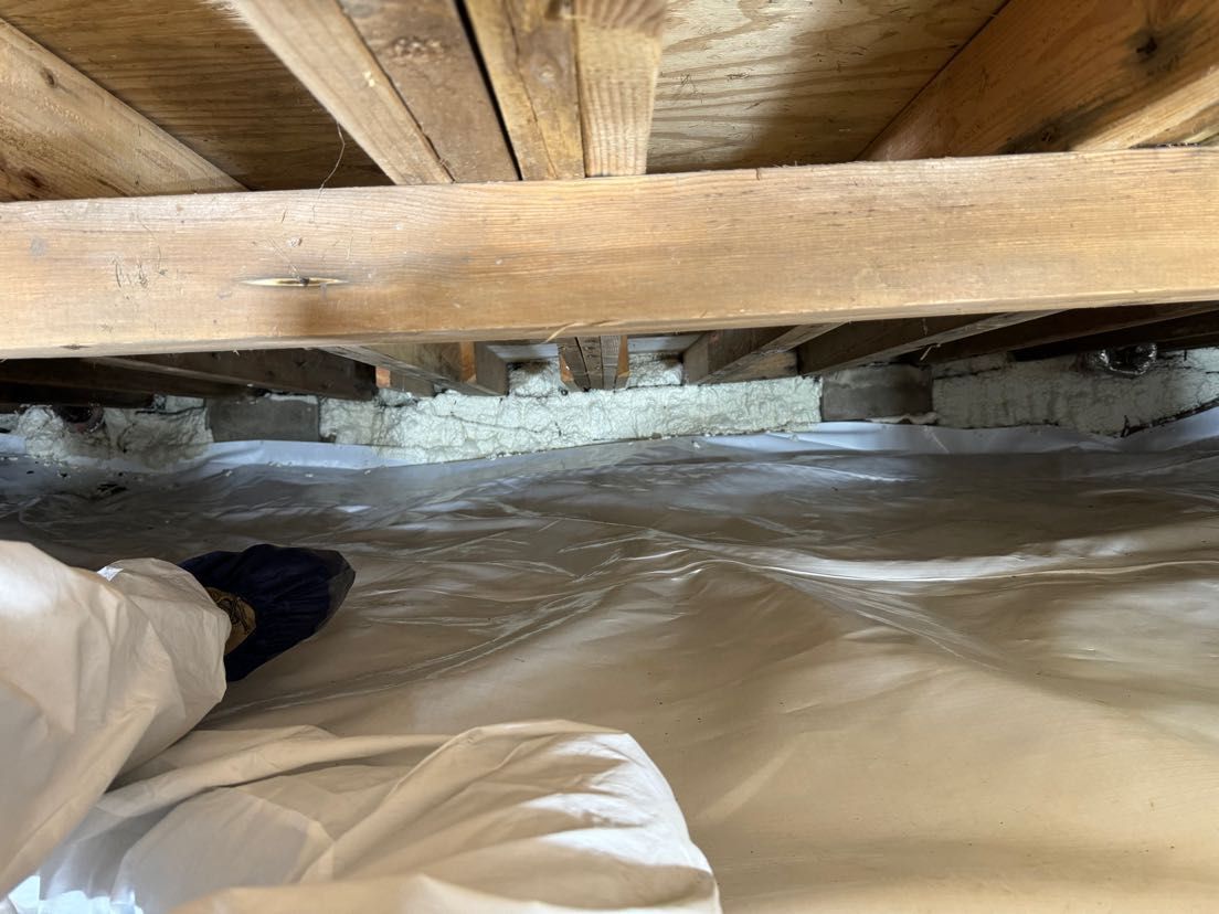 A person is standing under a wooden floor in a room.