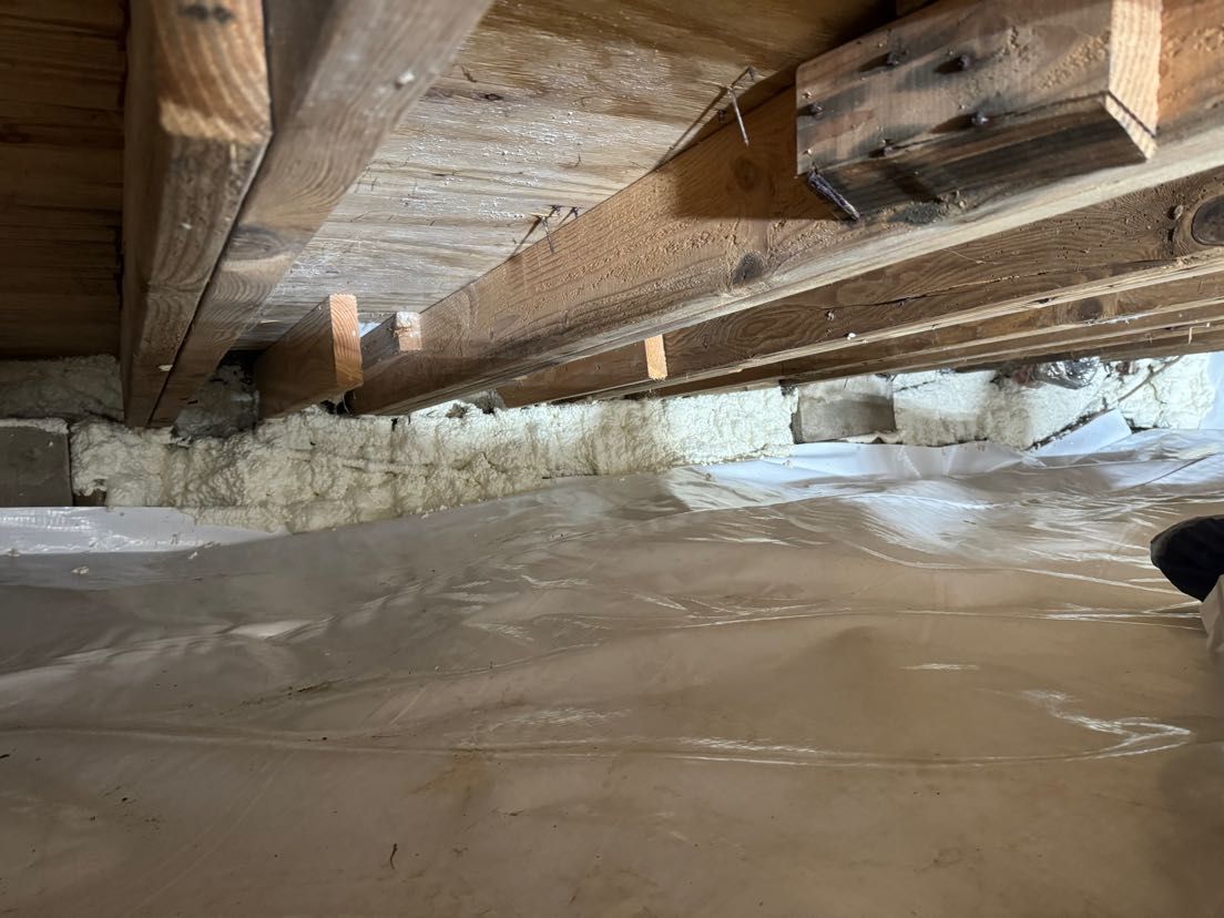A person is standing under a wooden beam in a basement.