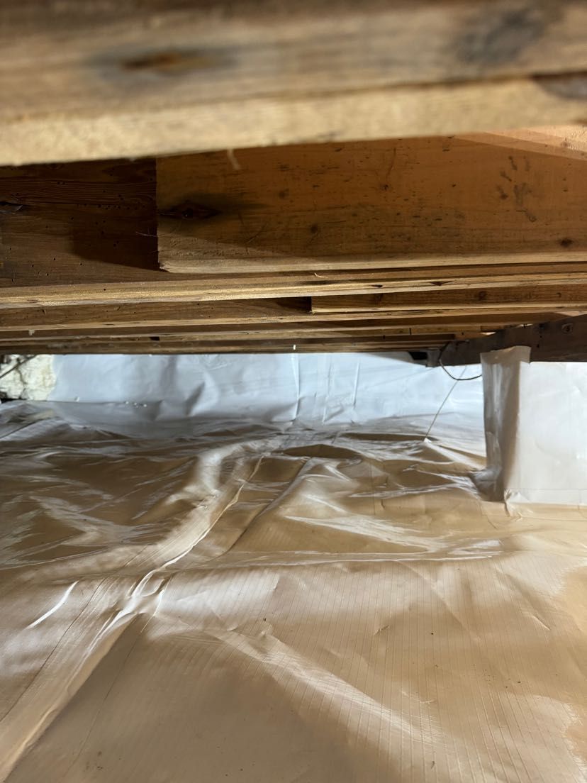 A wooden pallet is sitting on top of a white plastic sheet.