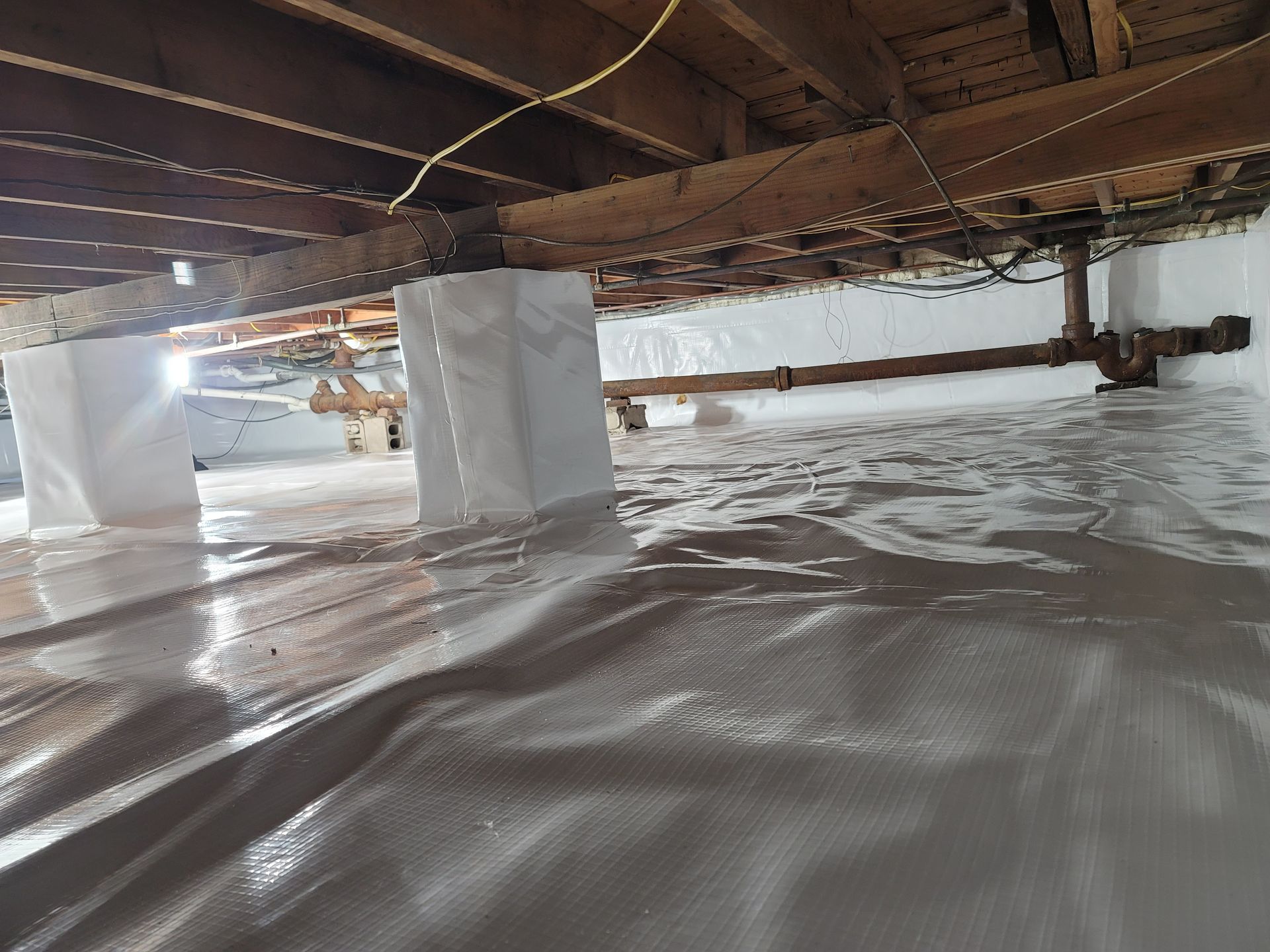 A crawl space under a house with a lot of water coming out of it.