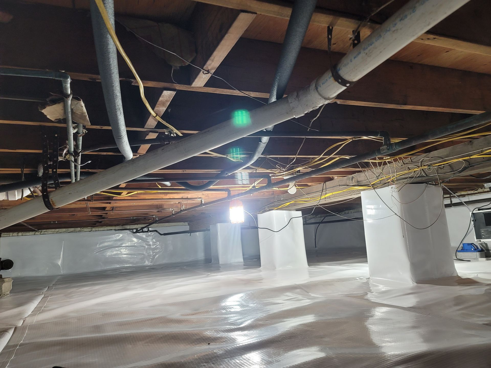 A basement with a lot of pipes and wires hanging from the ceiling.