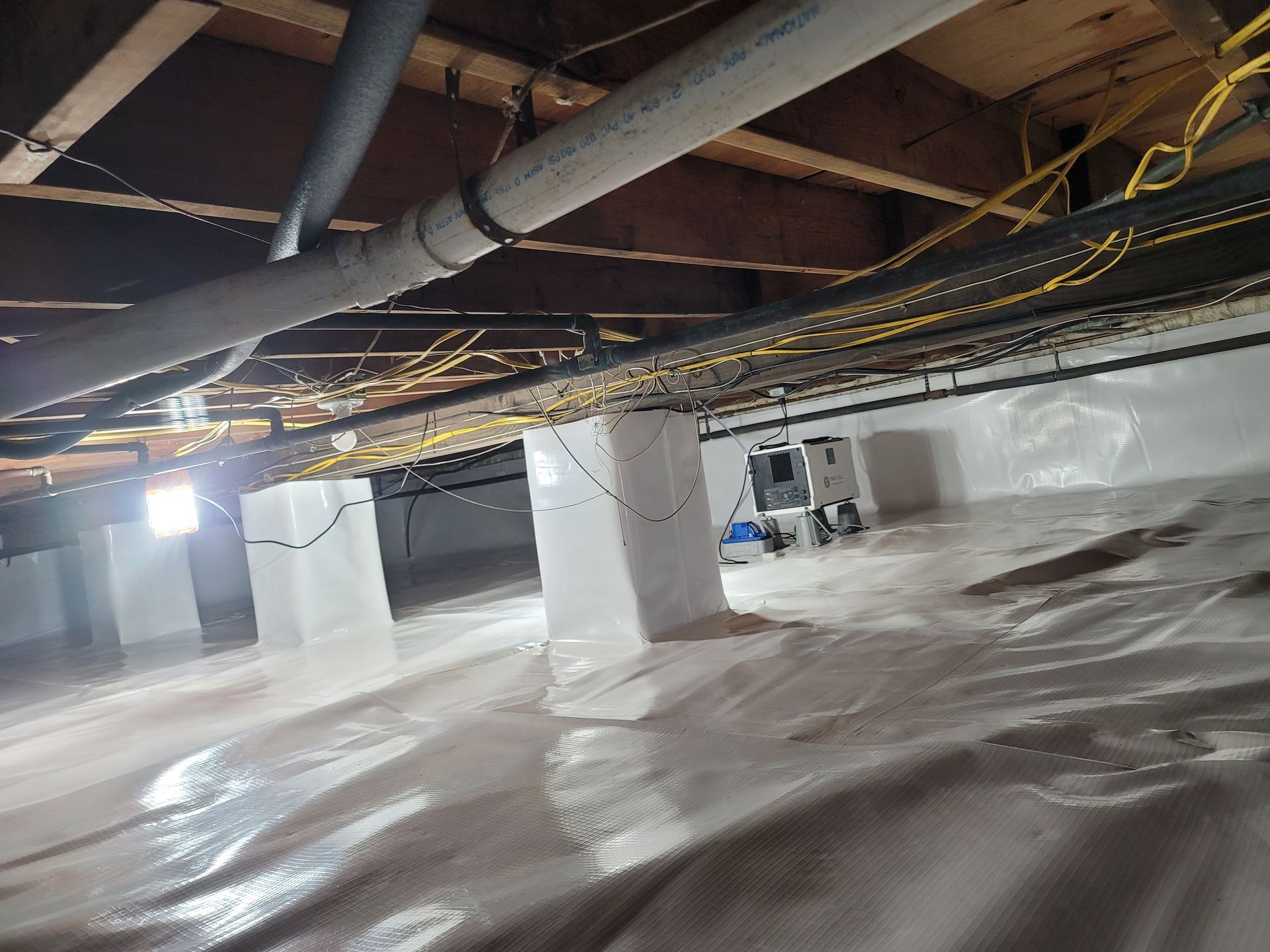 A basement with a lot of pipes hanging from the ceiling.