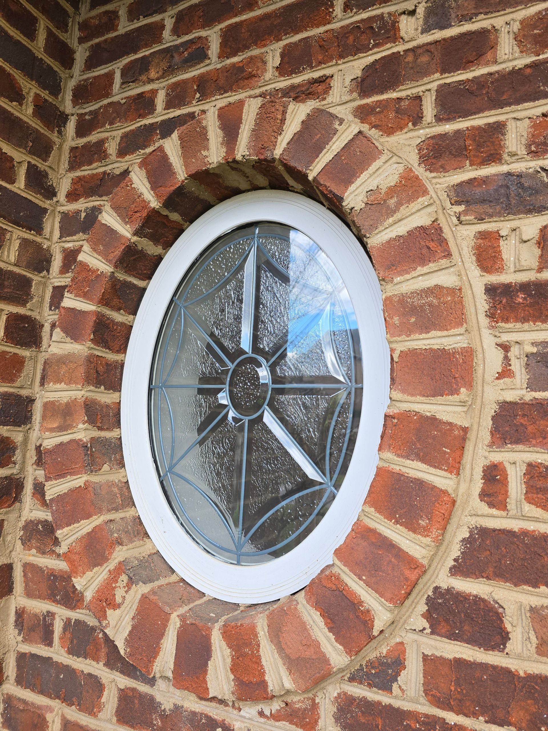 Oval stained-glass window set in a red brick wall