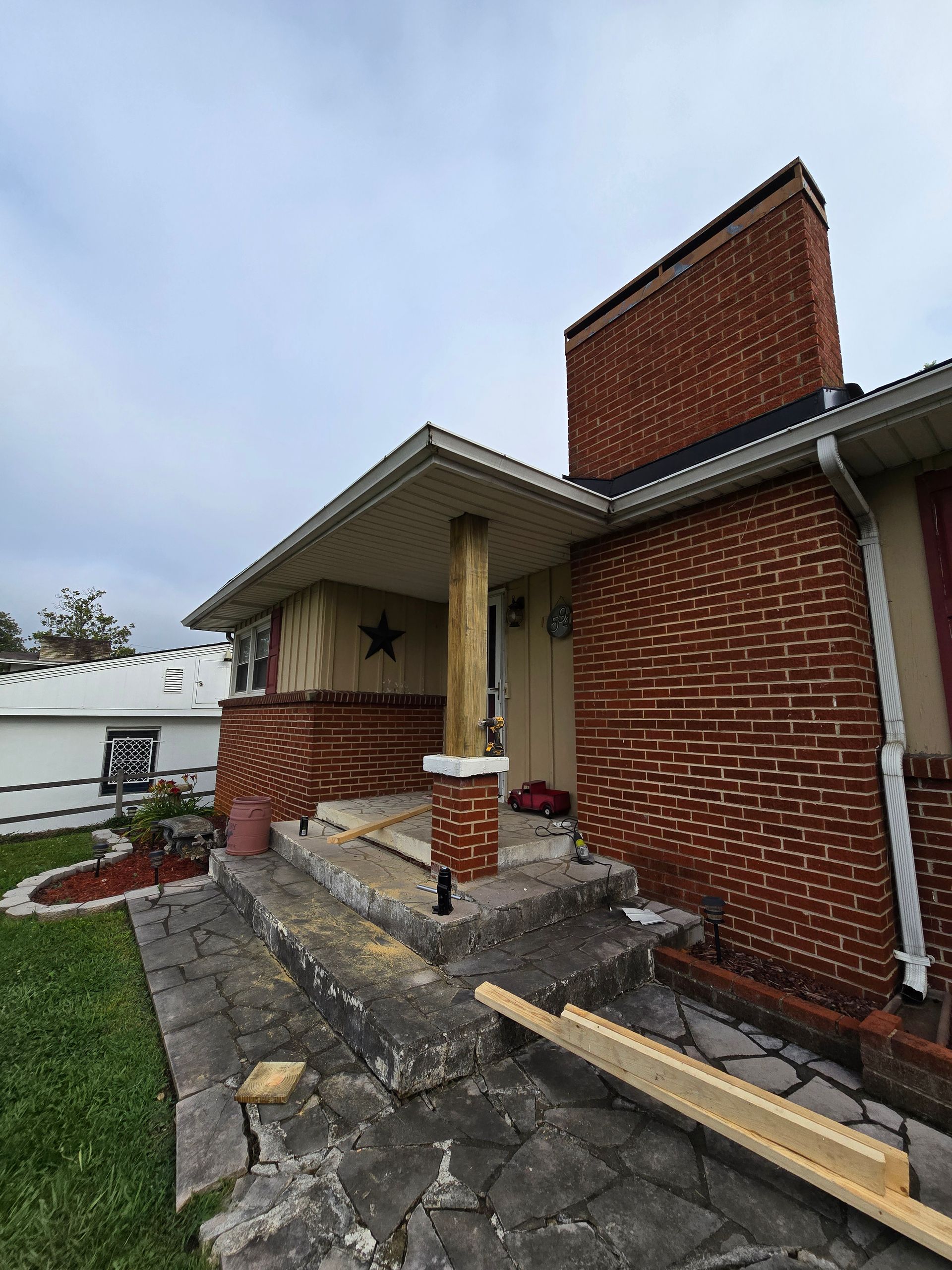 Front porch of a brick house with torn-up stone steps and debris along the walkway.