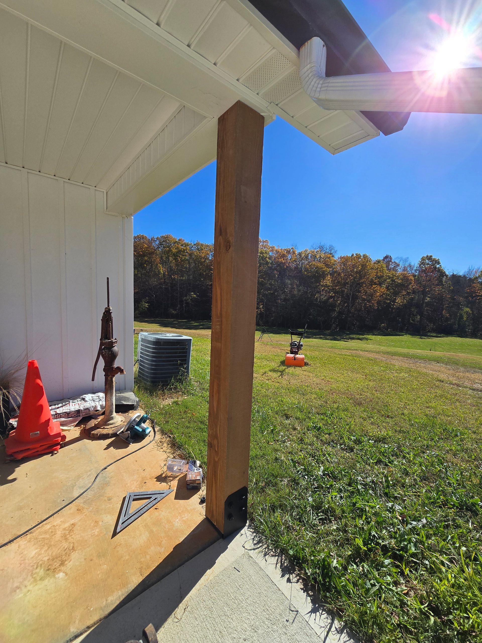 Covered patio with wooden post, orange cones, and green yard on a sunny day