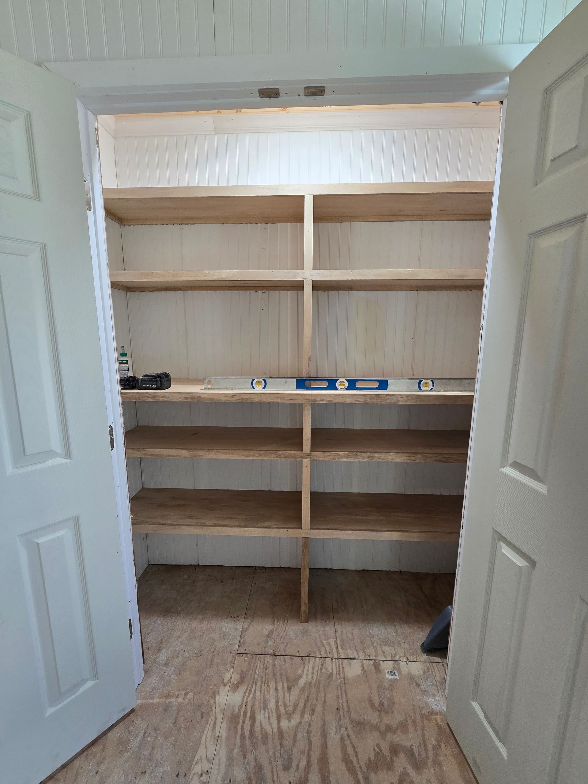 Open closet with white shelves and beige trim in a carpeted room, with shelves mostly empty.