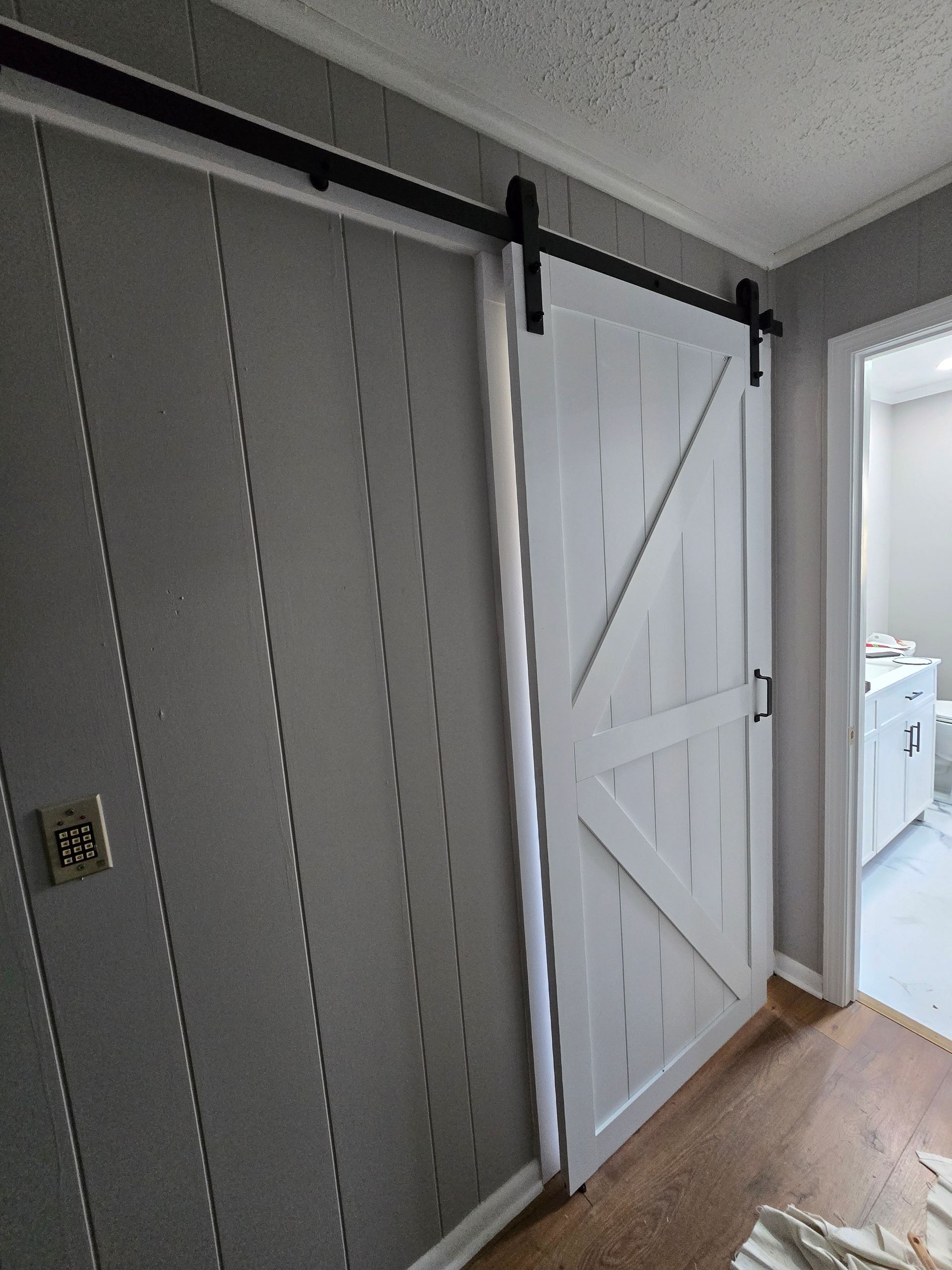 Interior hallway with a white sliding barn door on a black rail beside a window.