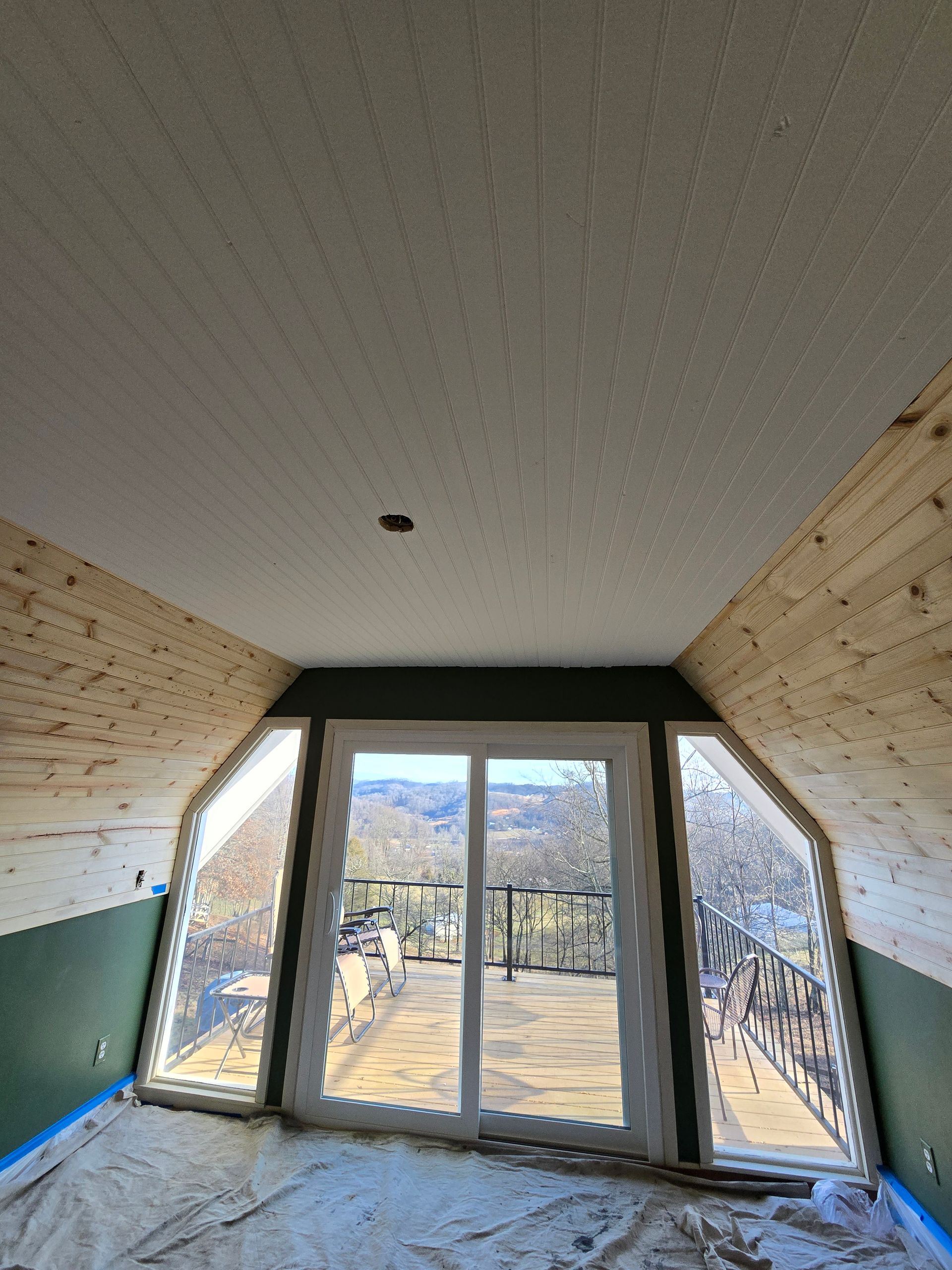 Interior hallway with sloped walls and glass doors opening to a sunny outdoor yard.