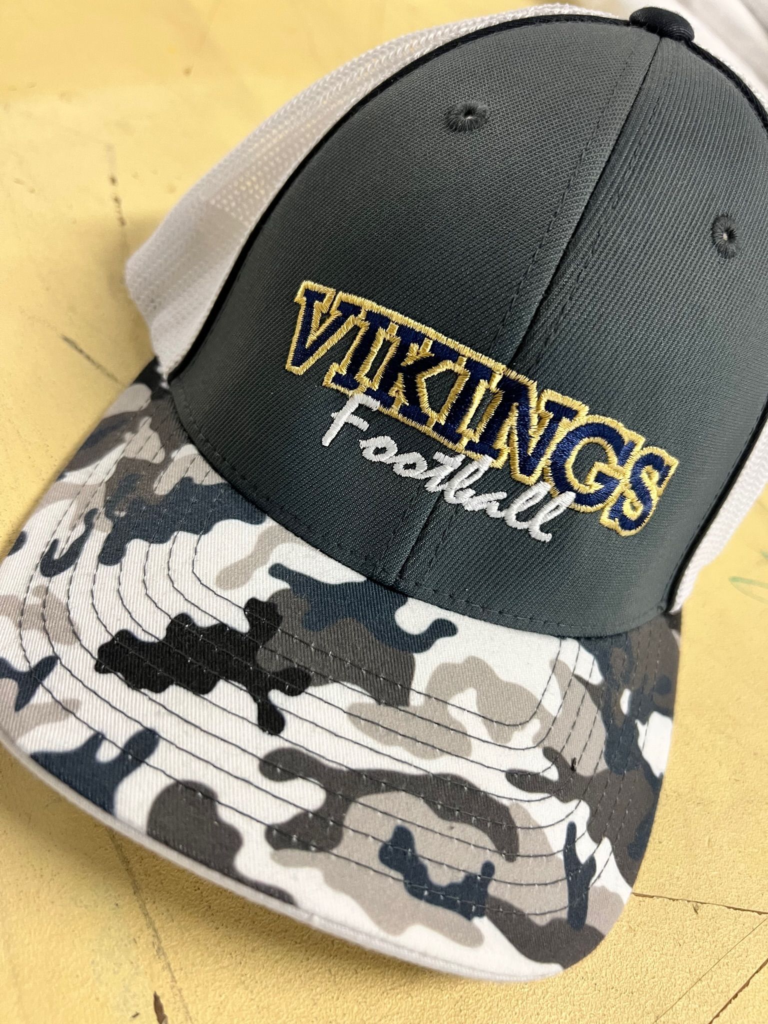 A grey and white camouflage baseball cap featuring