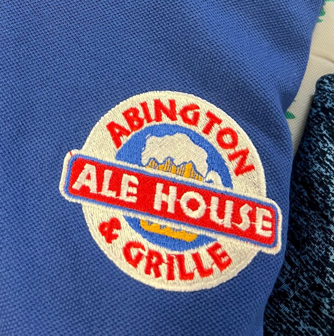 An embroidered circular patch on a blue fabric reading