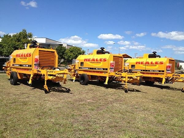 Three yellow reales trucks are parked in a grassy field