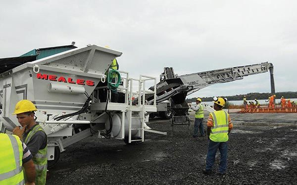 A group of construction workers are standing in front of a large machine.