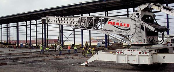 A white crane is parked in front of a building under construction.