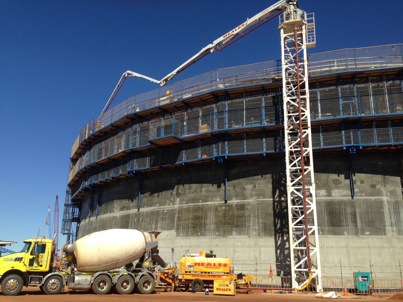 A concrete mixer truck is parked in front of a large building under construction.
