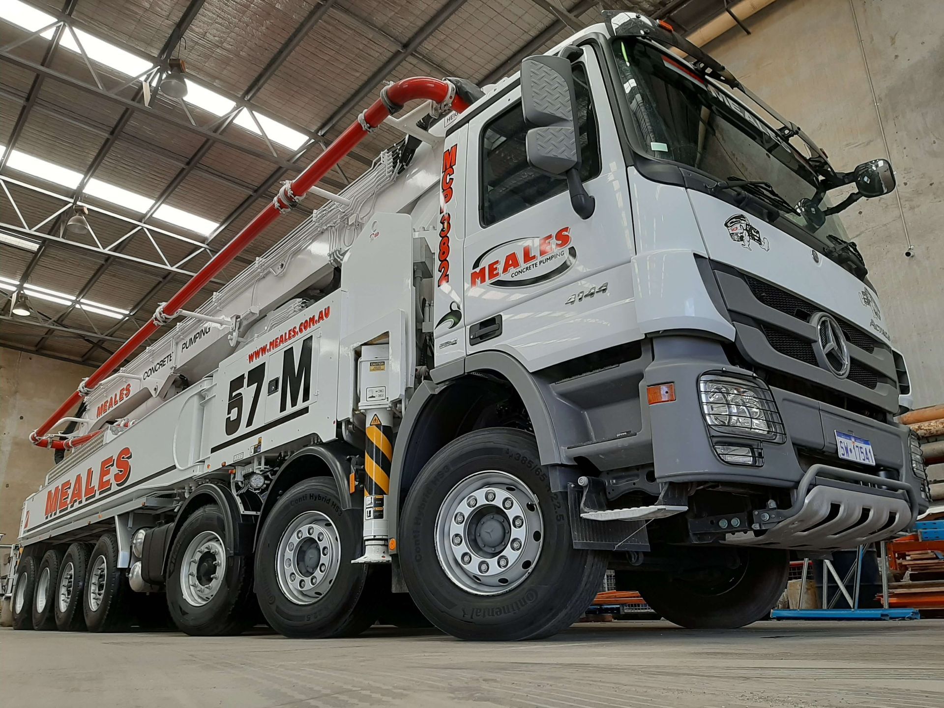 A concrete pump truck is parked in a warehouse.