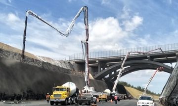 A concrete pump is being used to pour concrete on a bridge