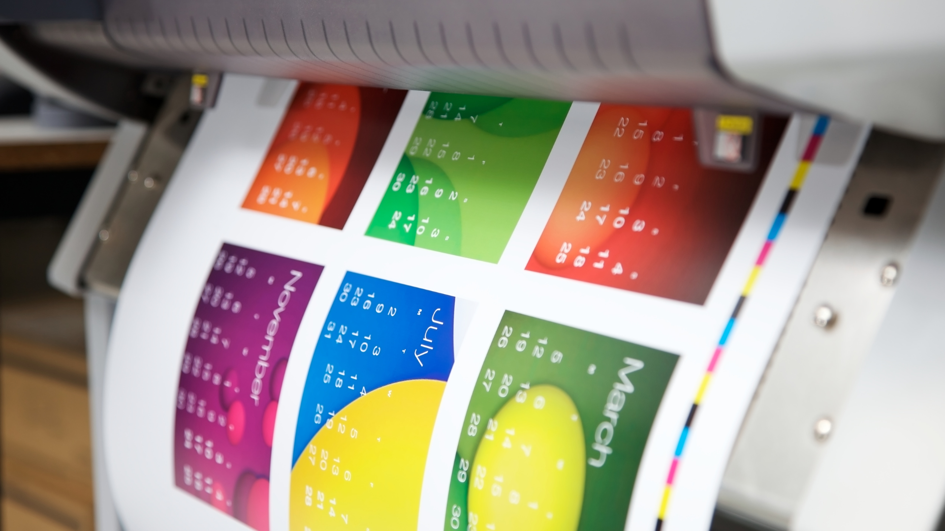 Printer outputting a colorful calendar with various months.